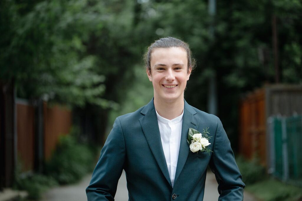 Teenage boy in a suit smiles at the camera.